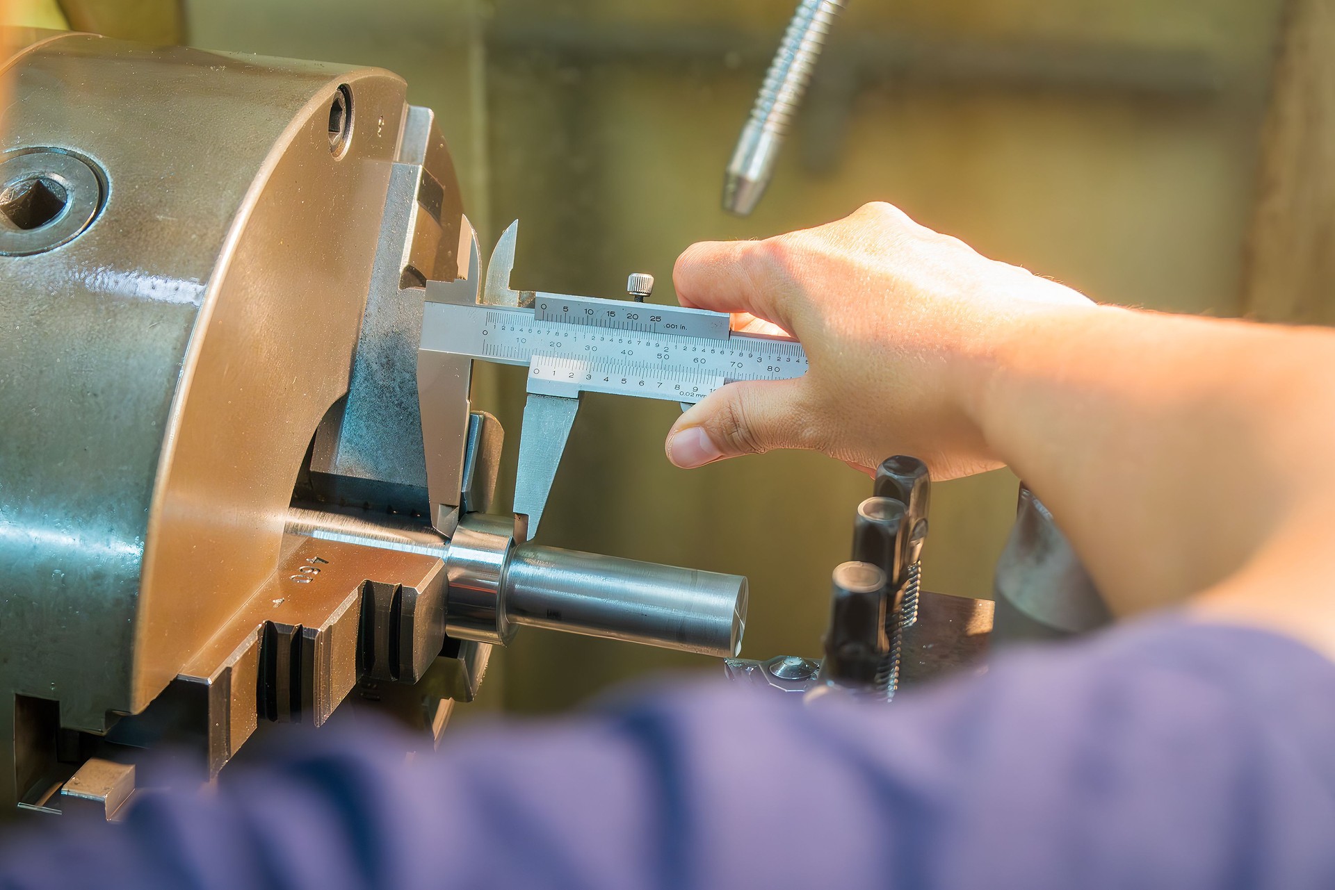 Close up scene the turning machine operator measuring dimension of metal shaft parts by Vernier caliper.